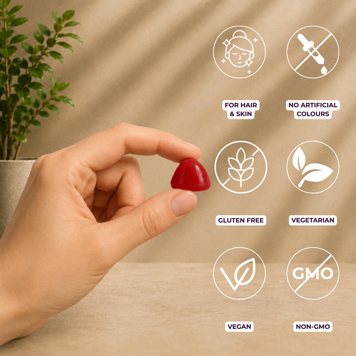 A hand holds a small red gummy against a warm beige background with soft leaf shadows. White circular icons with purple text highlight product benefits: for hair & skin ; no artificial colours; gluten free; vegetarian; vegan; and non-GMO